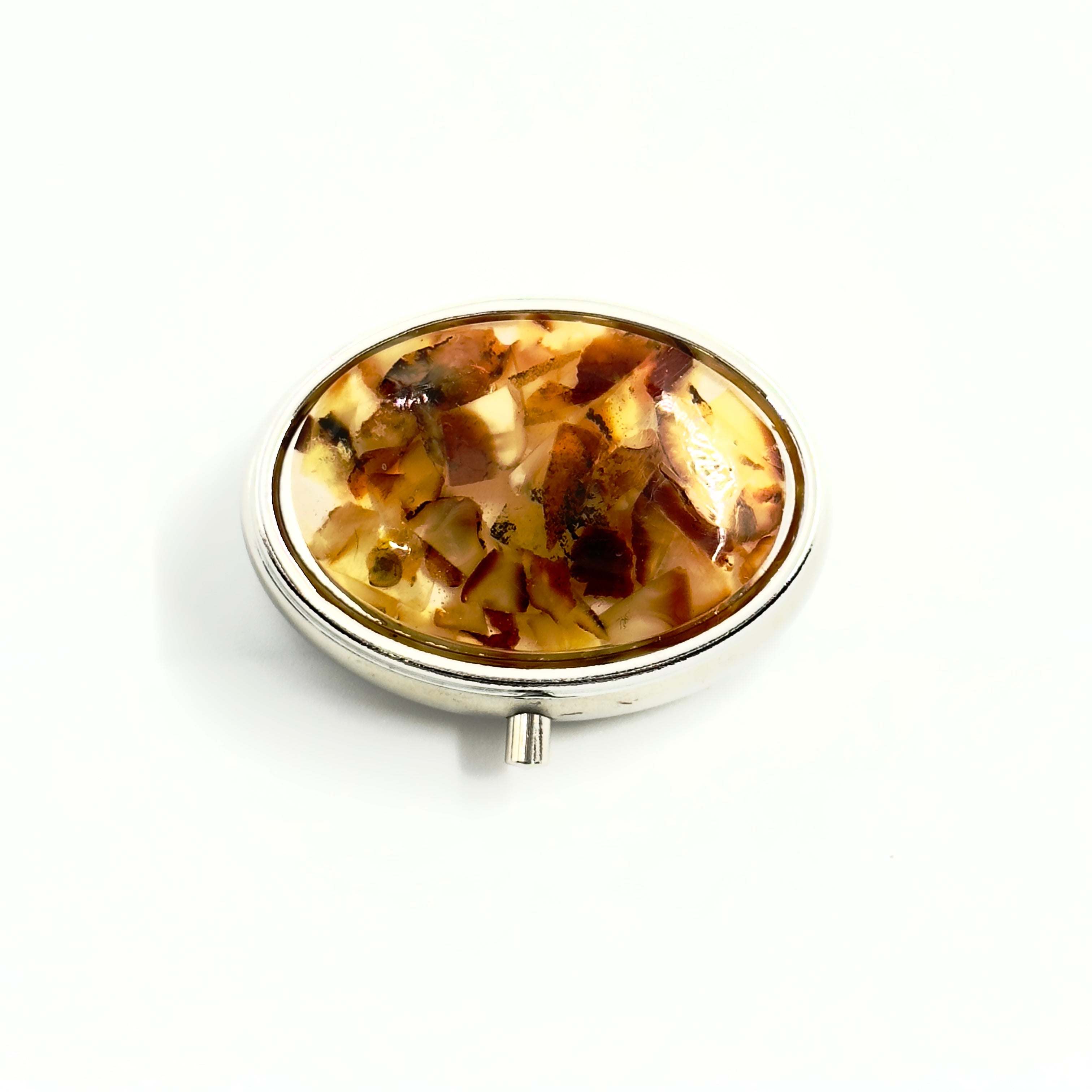 Round pill box with a tortoiseshell design on a white background