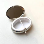 Small oval pill case with natural Baltic amber and metal construction