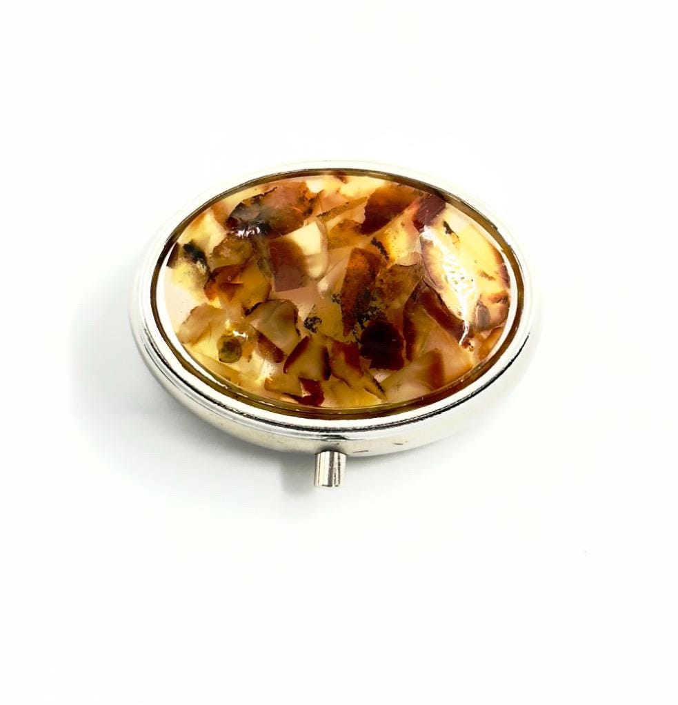 Handmade oval pill case featuring old milky Baltic amber and steel body