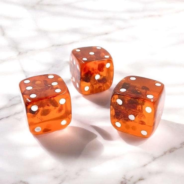 The image highlights the unique honey-golden and cognac tones that vary naturally from piece to piece. Handmade in Lithuania, this gemstone dice reflects traditional craftsmanship and the raw beauty of natural materials. No two dice are identical, making each one a one-of-a-kind collectible item. Perfect for board games, tabletop gaming, or decorative display, this amber dice is also suitable as a luxury gift for gamers, crystal lovers, or collectors of handmade goods.